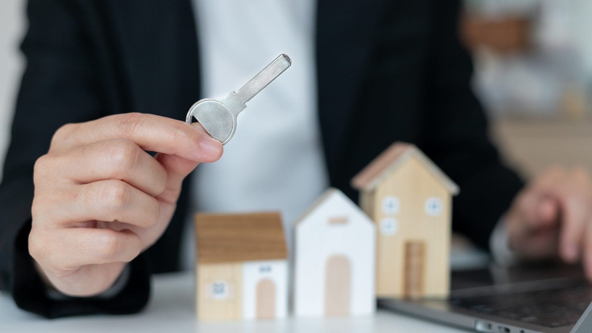A woman holding a key to her property after renting from her landlord, who seeks high rental yields. 